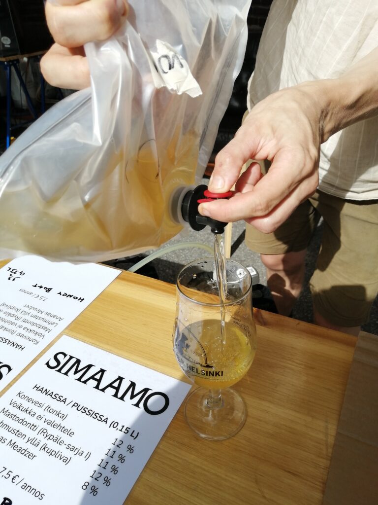Panimon edustaja laskee hunajaviiniä hanapussista lasiin